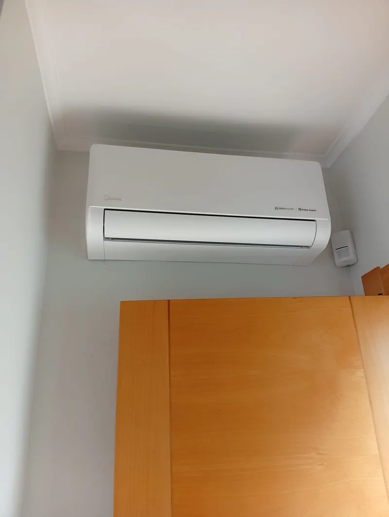 Ar condicionado split instalado na parede de um quarto em Lisboa, por cima do roupeiro.