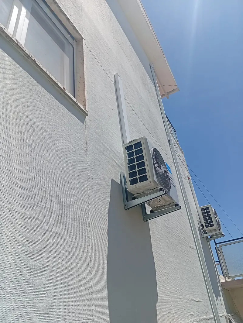 Unidade exterior de ar condicionado instalada no alto da fachada de uma moradia em Cascais.