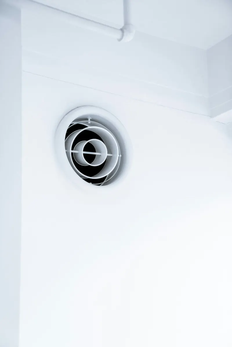 Boca de extração de ventilação mecânica controlada no teto de uma casa de banho.
